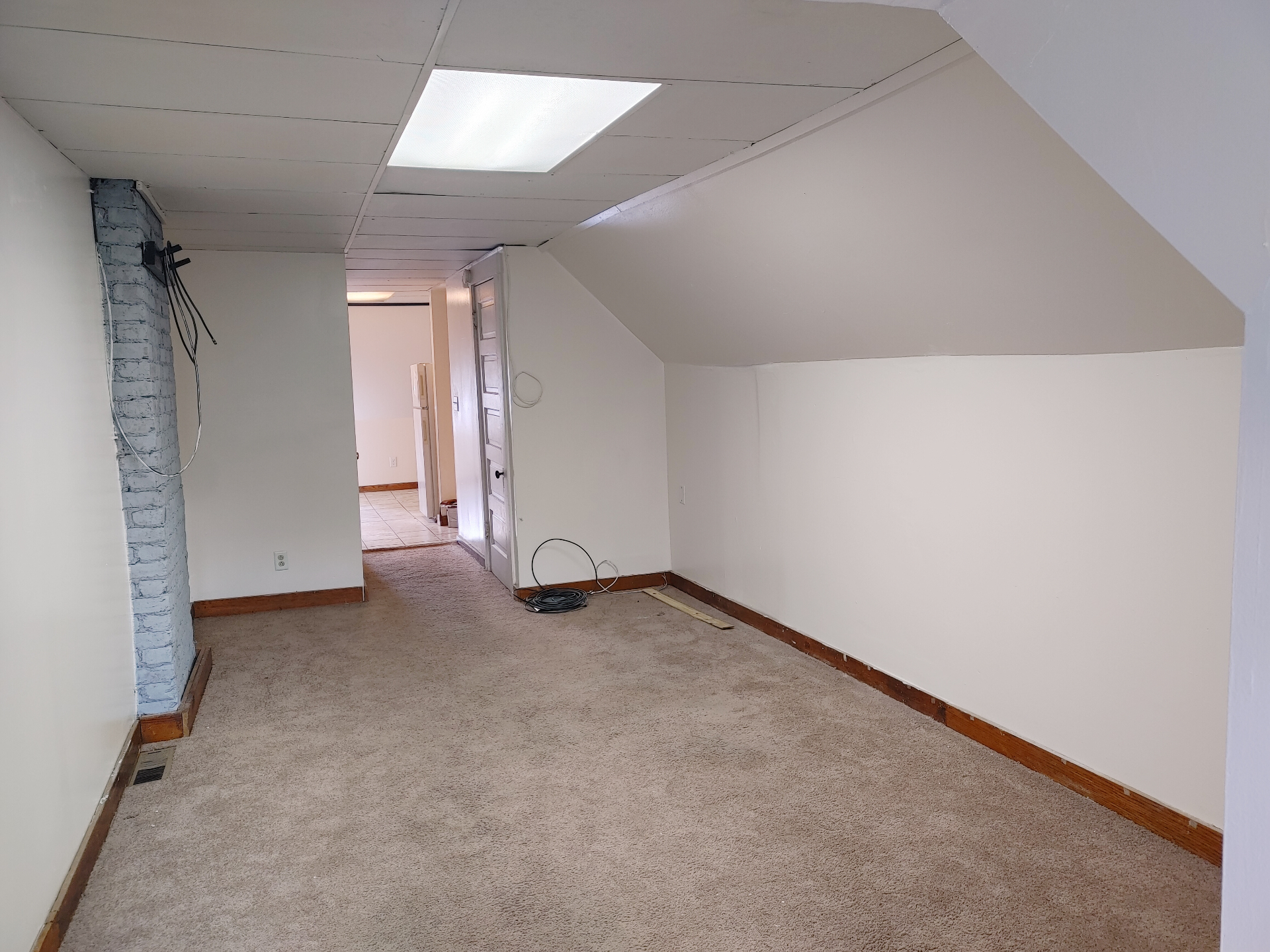 89 E Woodruff Ave. Unit C bedroom with sloped ceilings, painted brick chimney, and carpet