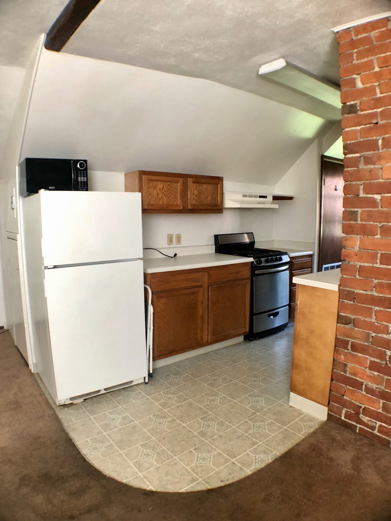 Wide view of galley kitchen with fridge, microwave, and tile floor