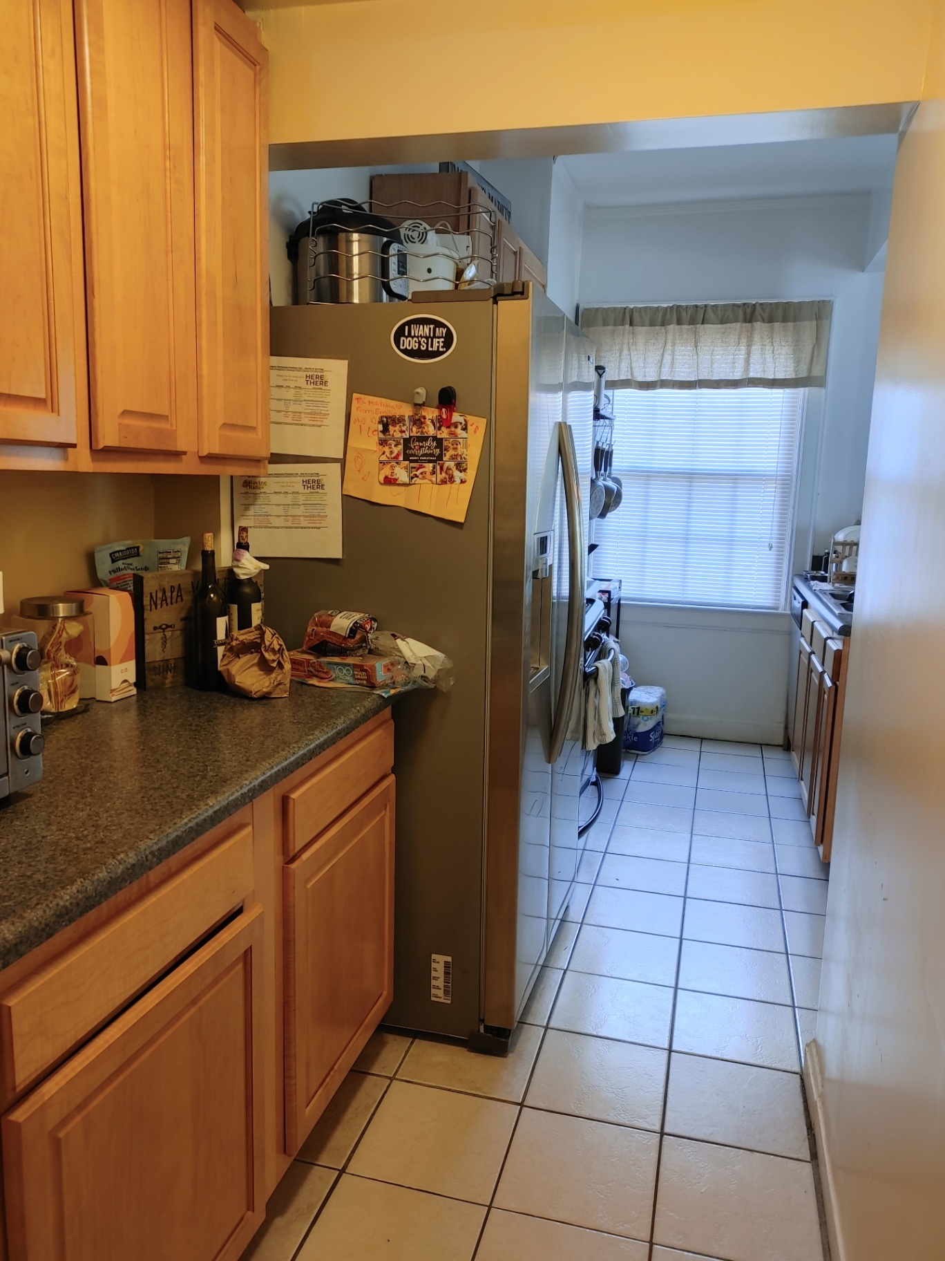 Unit G kitchen with wood cabinets, granite counters, and stainless side-by-side fridge