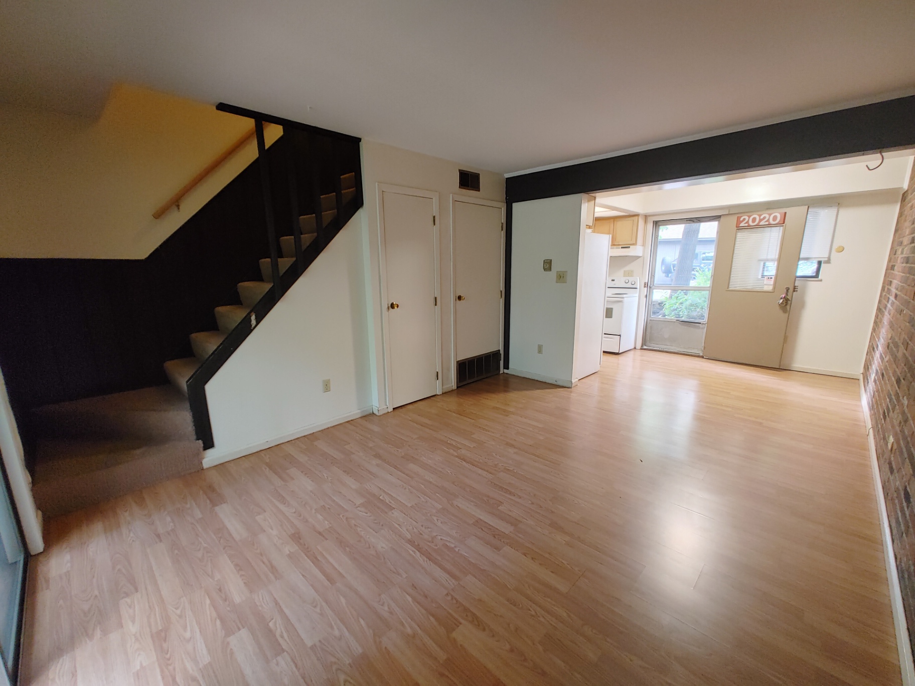 2016 Iuka Ave. open living room with exposed brick wall, staircase, and kitchen entry