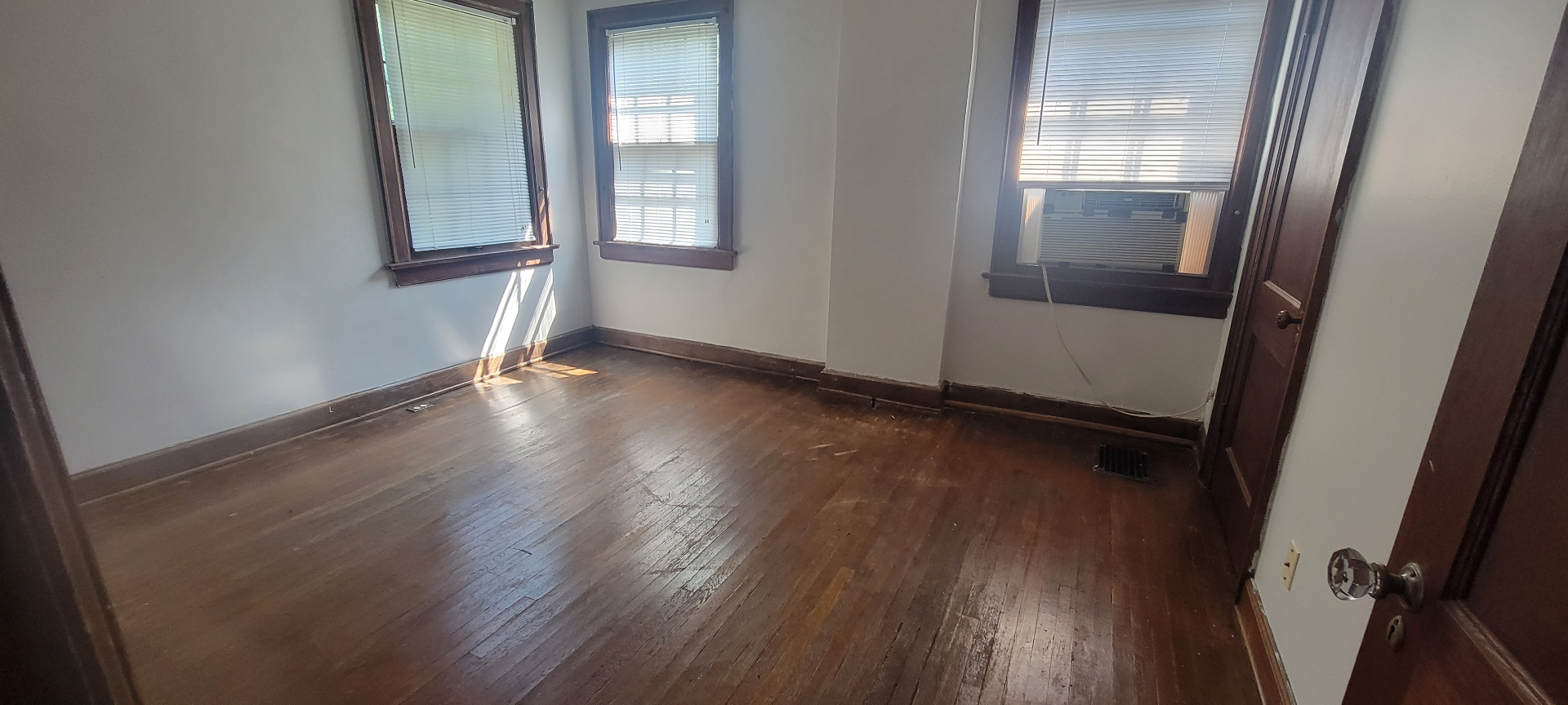 2044 Iuka Ave. C spacious bedroom with three windows, hardwood floors, and window AC
