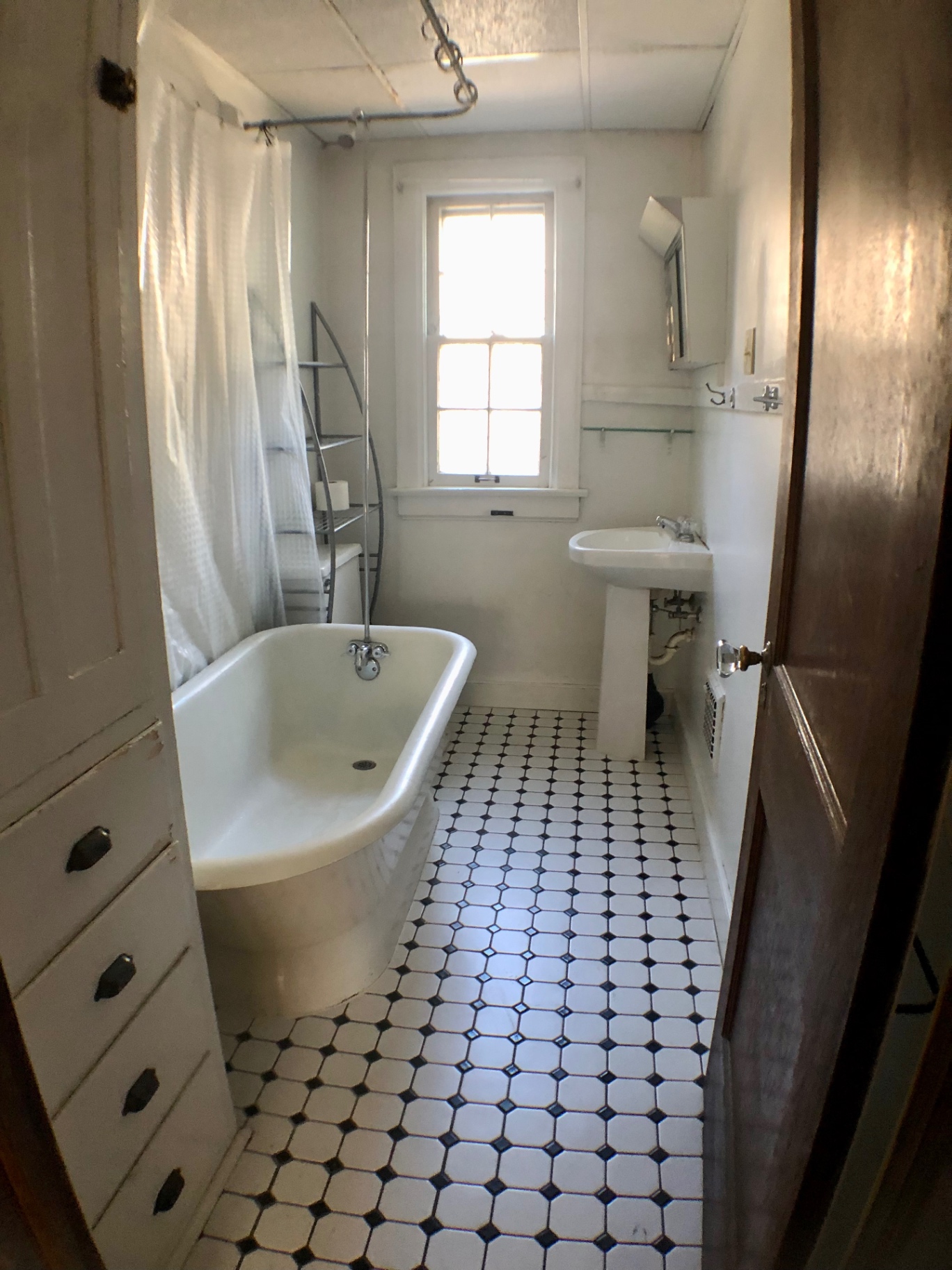2044 Iuka Ave. A vintage bathroom with clawfoot tub, pedestal sink, and black-and-white tile floor