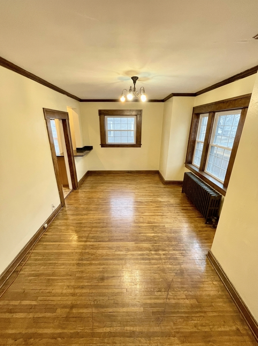 Unit D dining room with chandelier, radiator, and hardwood floors