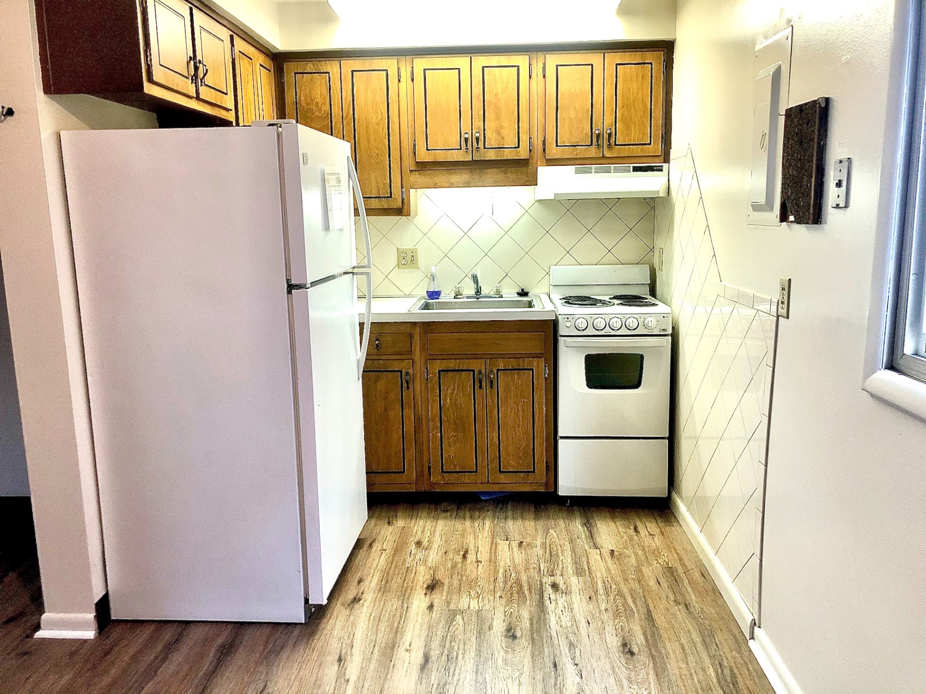 2011 Summit St. Unit D kitchen with wood cabinets, white appliances, tile backsplash, and plank flooring