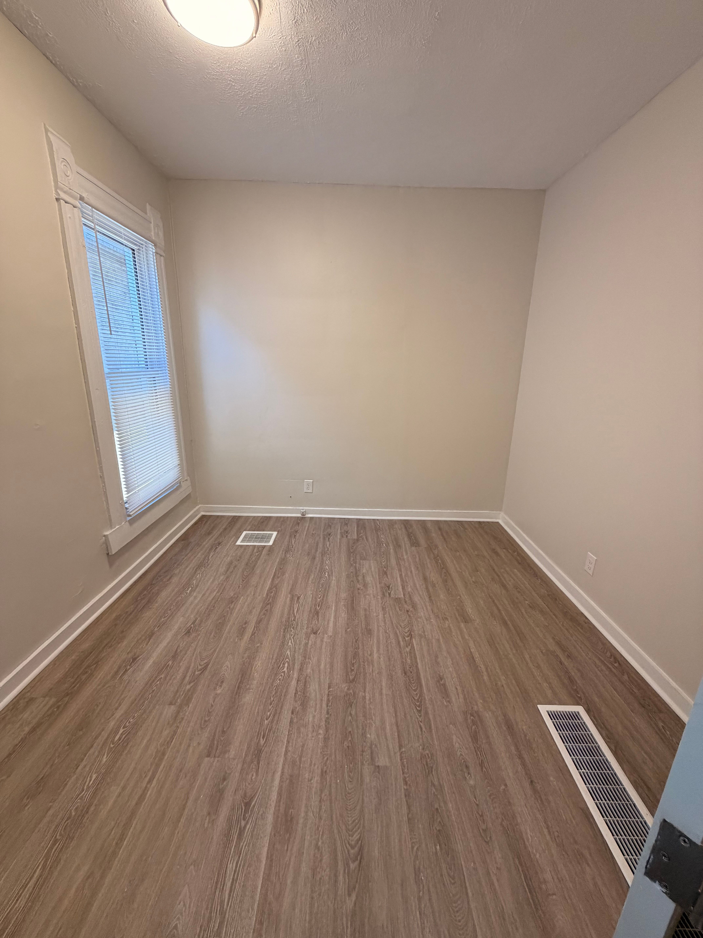 133½ bedroom with large window, plank flooring and freshly painted walls