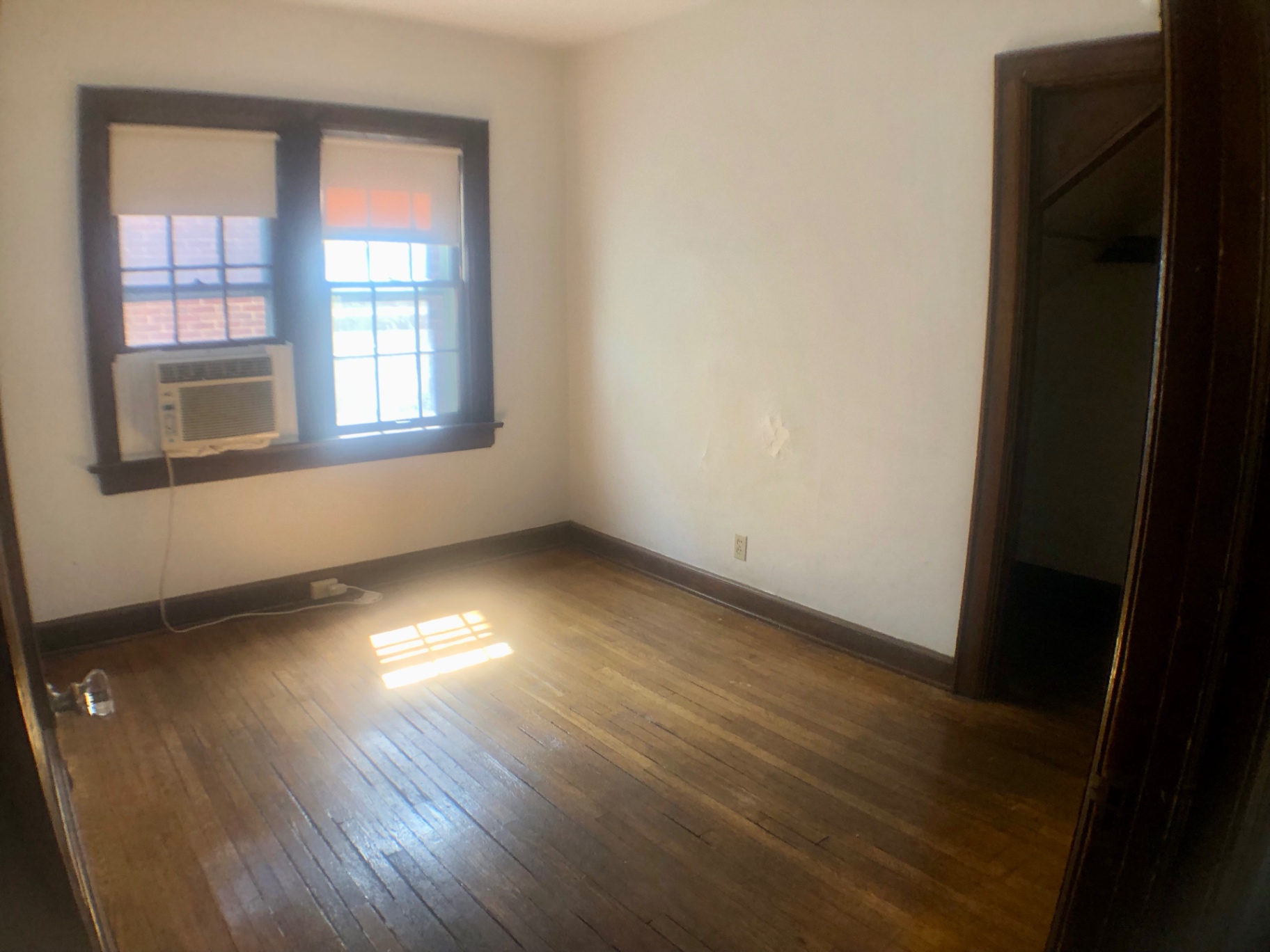 2044 Iuka Ave. A bedroom with window AC unit, hardwood floors, and dark wood trim