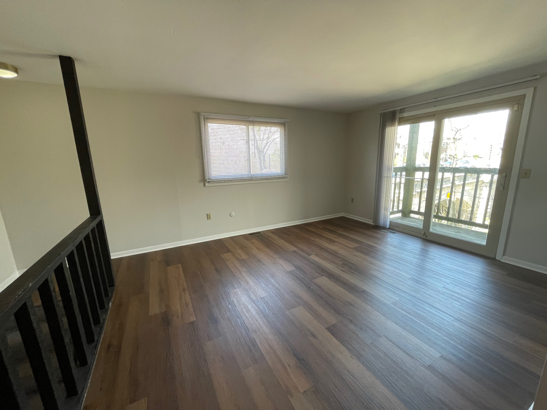 2020 Summit St. open living room with warm plank floors, large window, and sliding glass doors to the private balcony