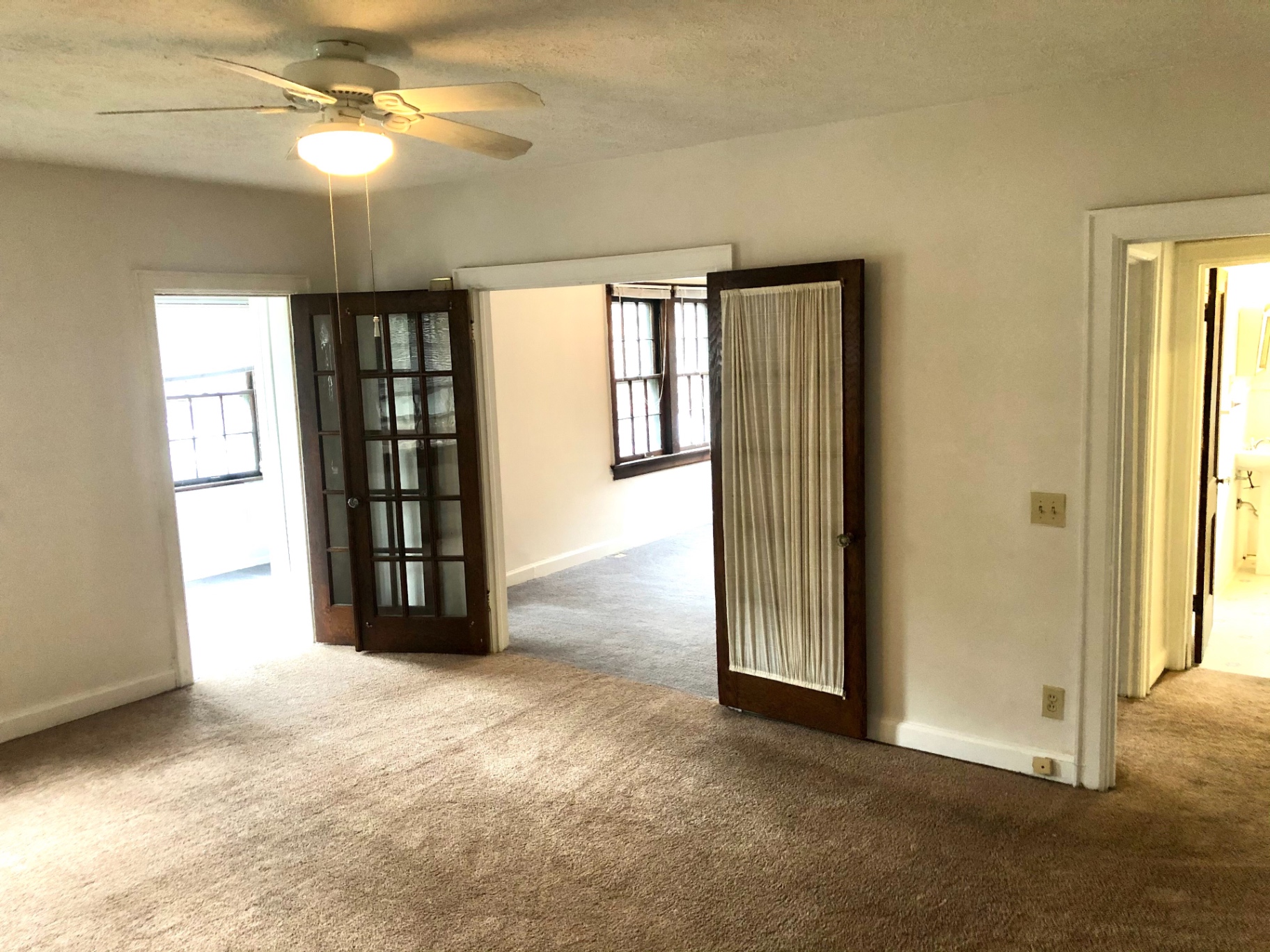 2044 Iuka Ave. B open living space with original French doors and ceiling fan connecting multiple rooms