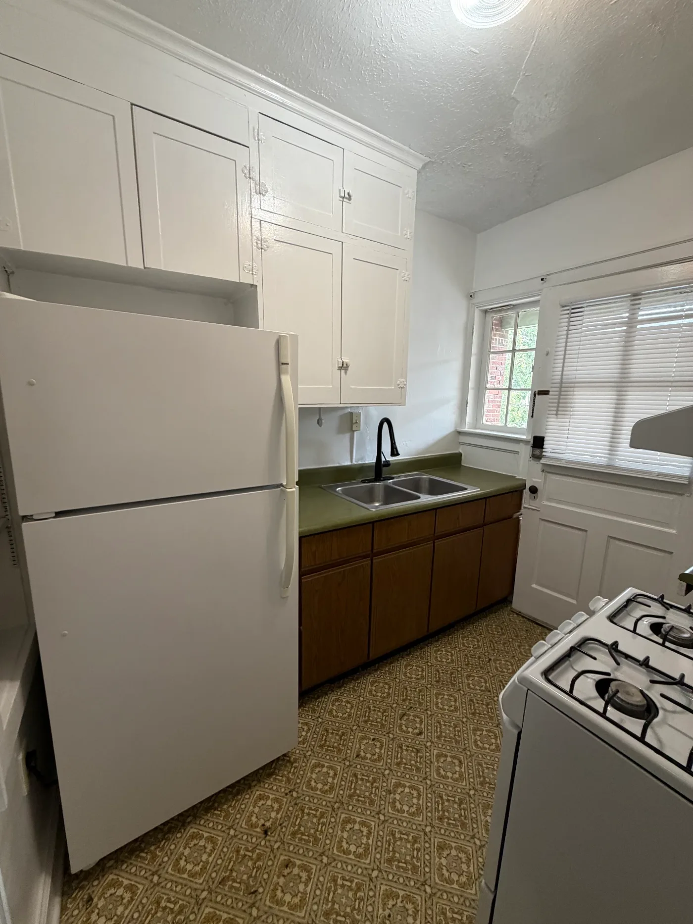 2048 Iuka Ave. D kitchen with full-size refrigerator, double stainless sink, and tall white cabinets