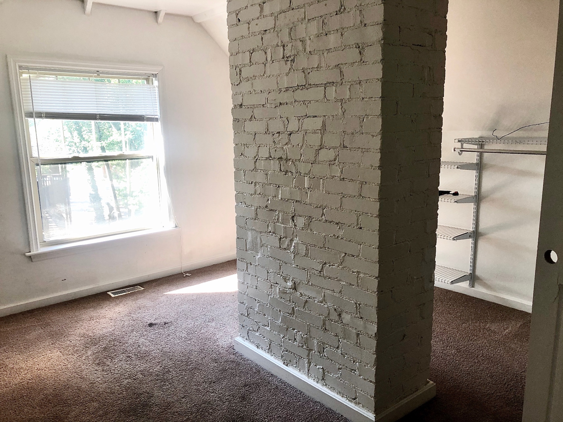 2034 Iuka Ave A upstairs bedroom with painted brick chimney and built-in closet shelving