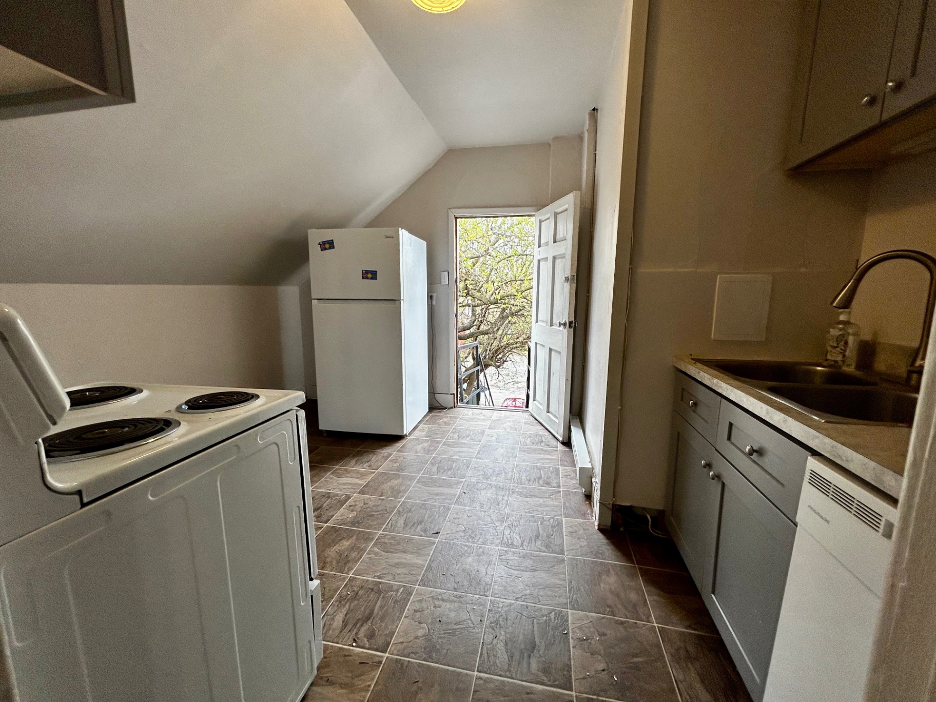 1820 Summit St. kitchen with full-size fridge and open rear door bringing in natural light