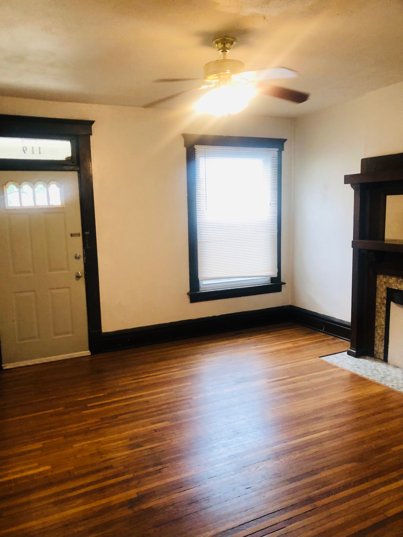 119 W 9th living room with front door, large window and dark wood trim