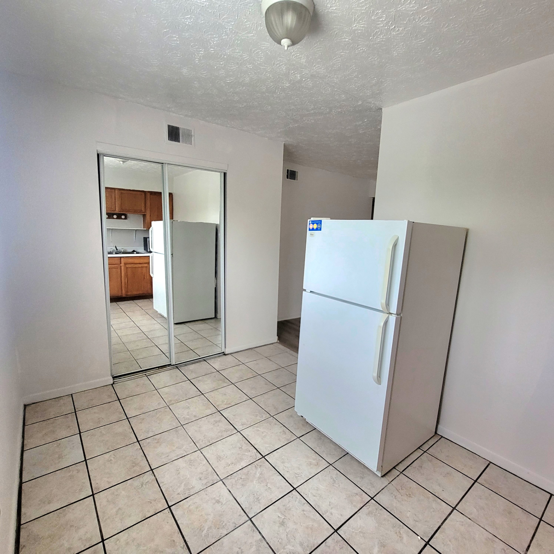 2150 N 4th St. Unit F tiled dining area with white refrigerator and mirrored closet doors