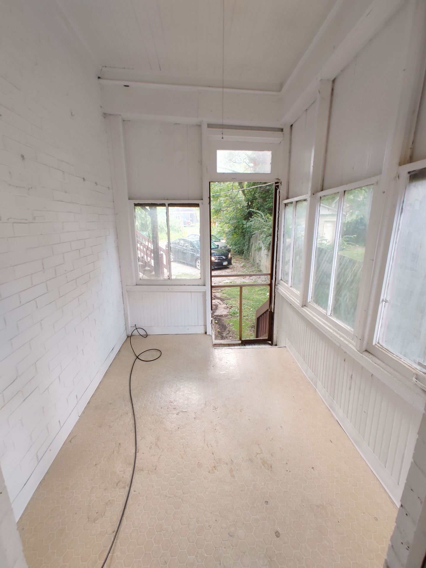 374 A E 14th Ave. rear enclosed sunroom with painted brick wall and screened back door