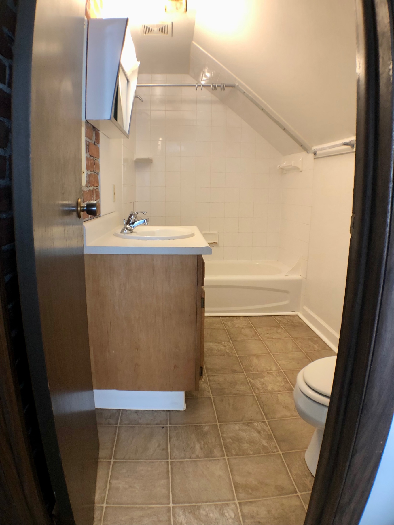 Full bathroom with tub, tile surround, vanity, and sloped attic ceiling