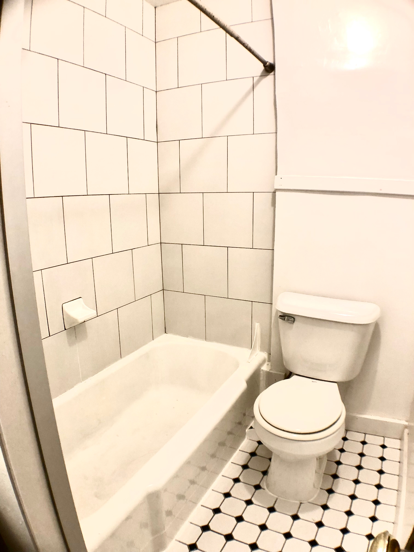 2054 Iuka Ave. D bathroom with large-format white subway tile tub surround and vintage black-and-white hex tile floor