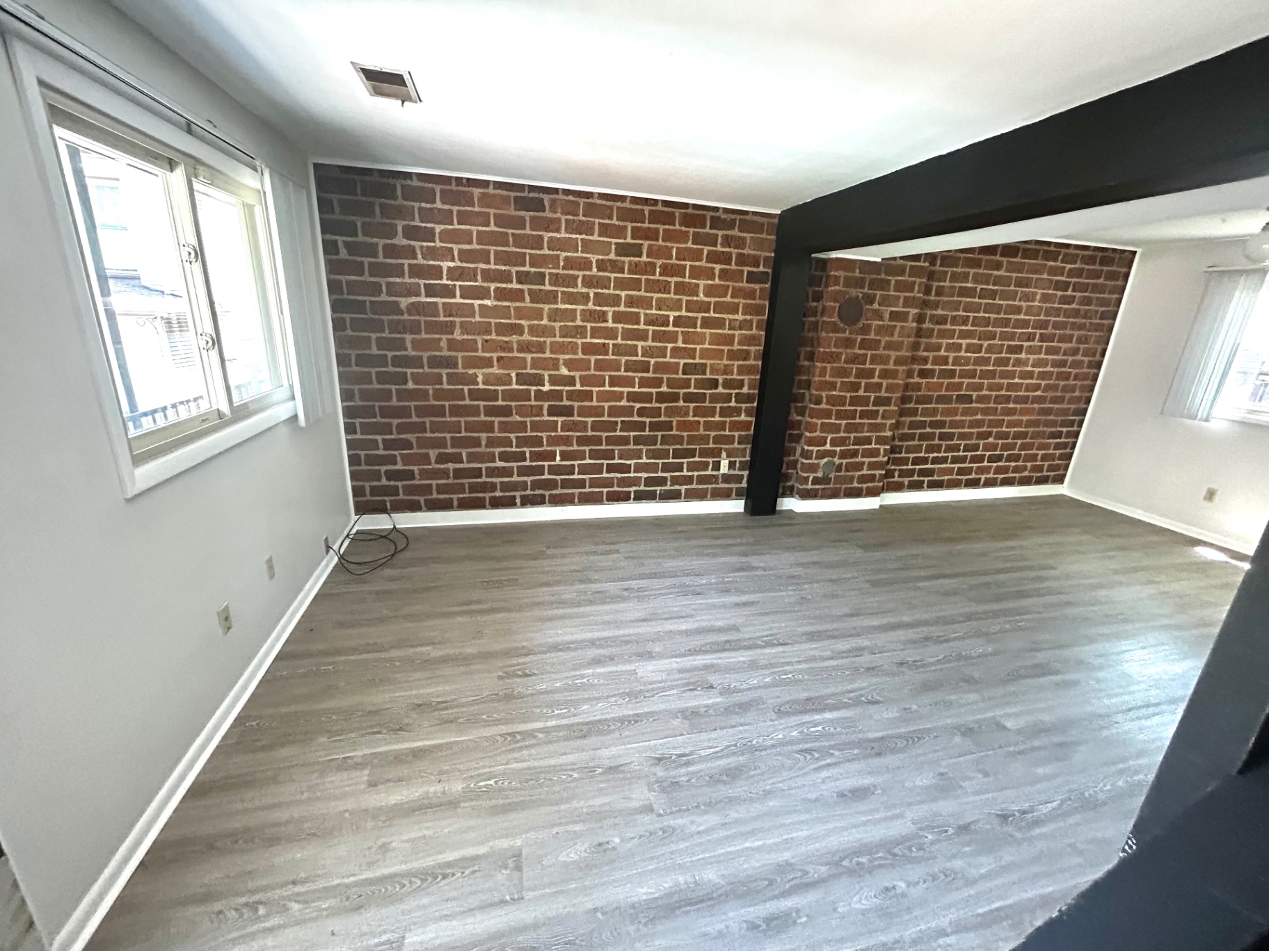 2011 Summit St. Unit E living room with bright corner window and exposed brick accent walls