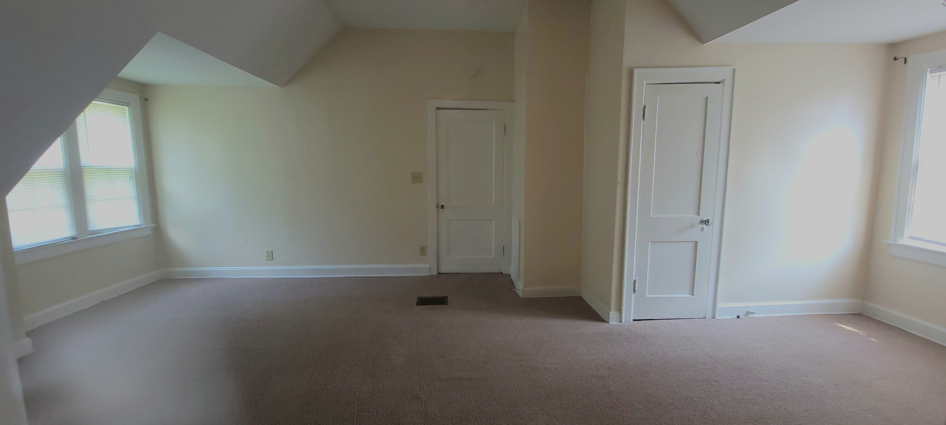 2054 Iuka Ave. C large carpeted bedroom with sloped ceilings, double windows, and extra storage doors