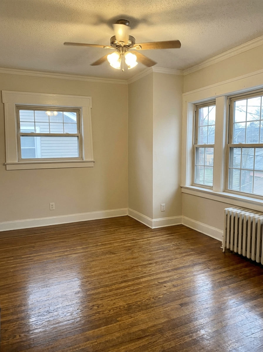 Unit H bedroom with ceiling fan, hardwood floors, and radiator