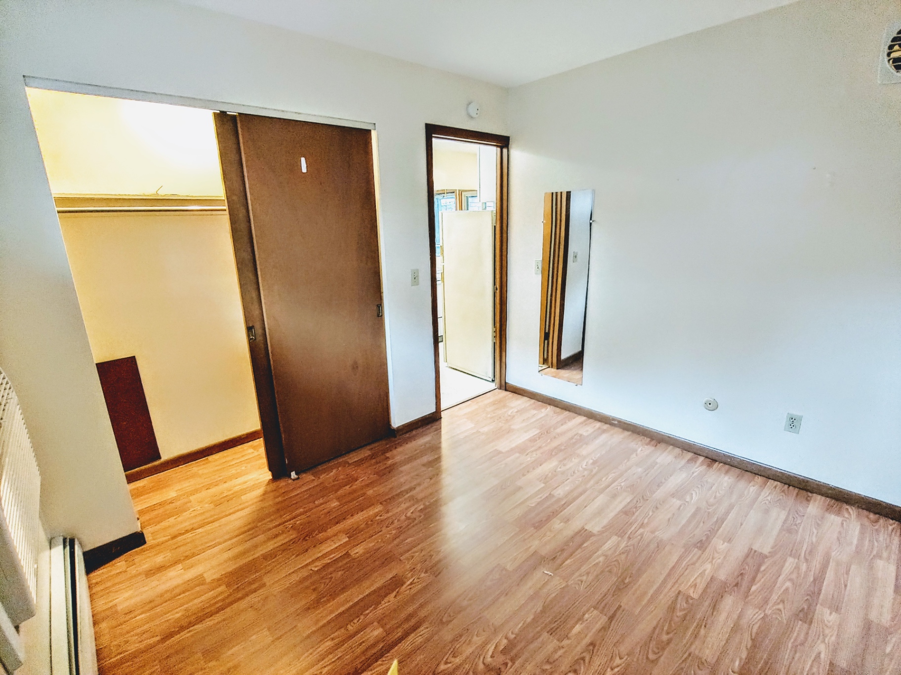 2040 Iuka Ave. 2A bedroom with sliding closet doors, full-length mirror, and wood laminate floors