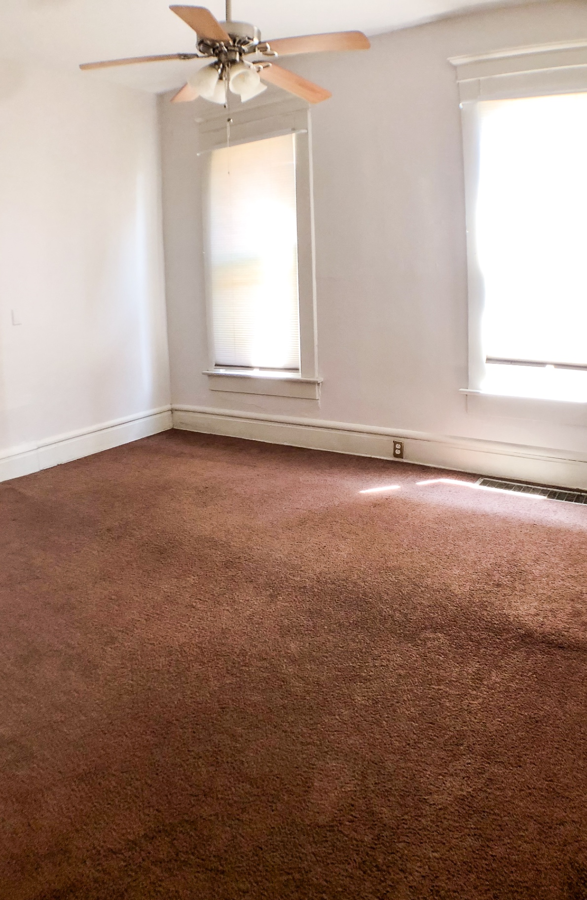 Unit A primary bedroom with ceiling fan, dual windows and plush carpet