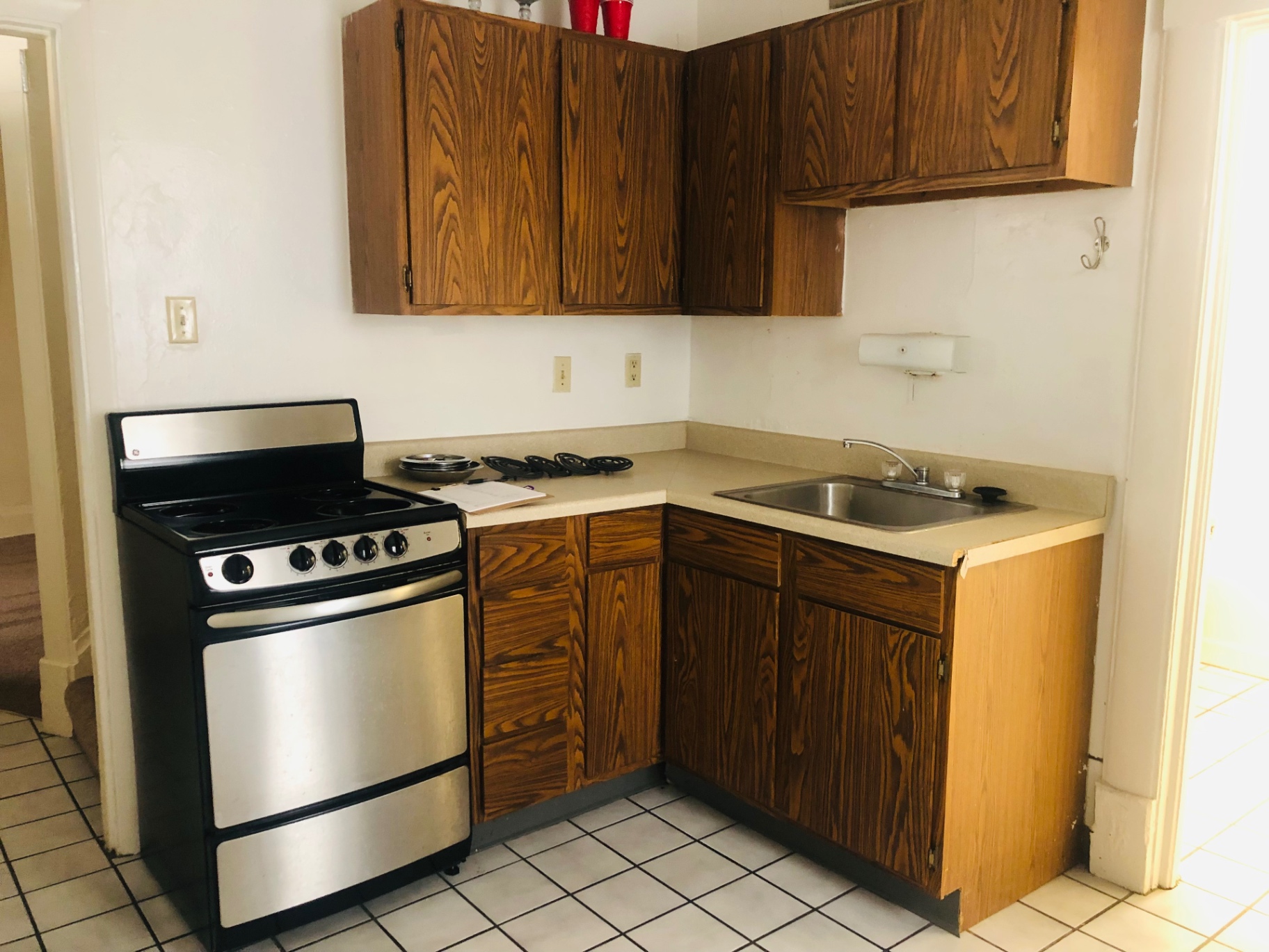 Rear unit kitchen corner with electric range, sink and wood cabinets