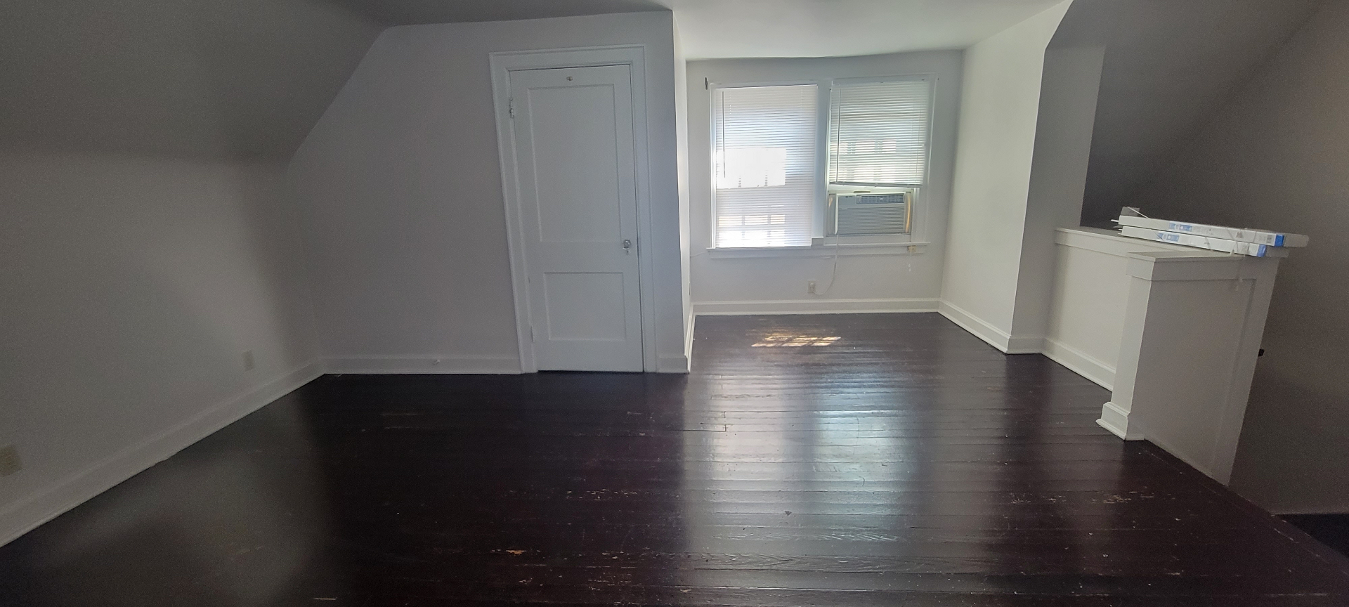 2044 Iuka Ave. C upper-level room with window AC, dark floors, and generous flex space