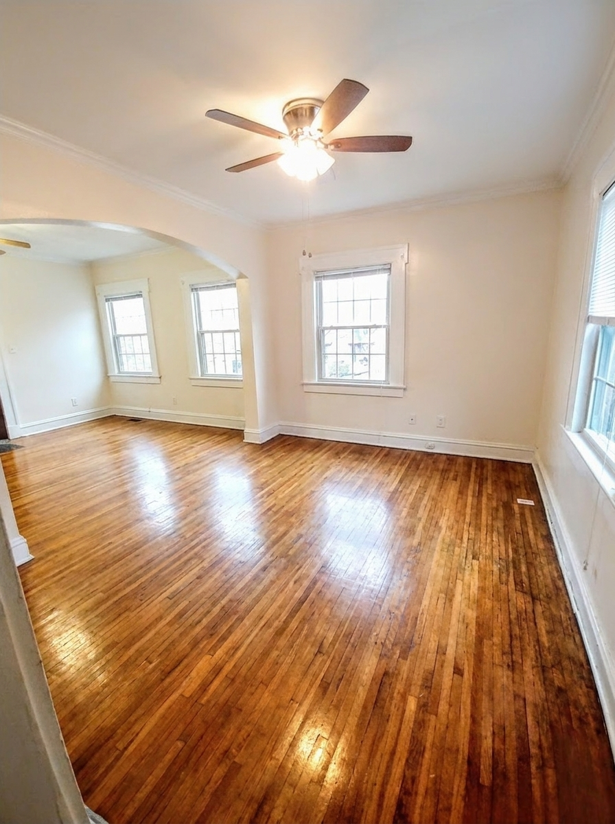 Unit I living area with hardwood floors, ceiling fan, and large windows