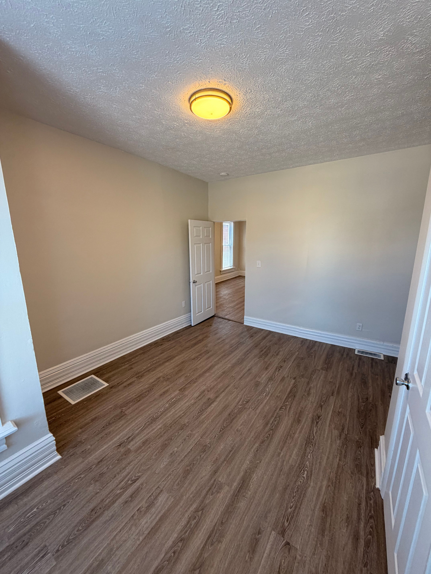133½ bedroom view toward the doorway with warm natural light and updated flooring