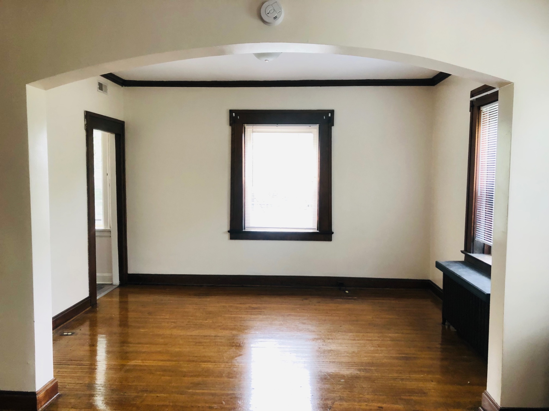 Unit F dining room with arched entryway, hardwood floors, and window seat