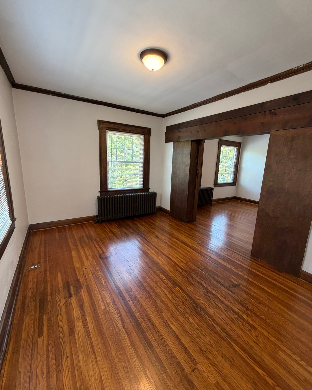 Bedroom with large windows, cast iron radiators, and hardwood floors